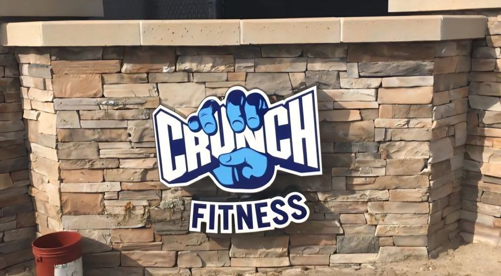 Crunch Fitness logo on stone wall.