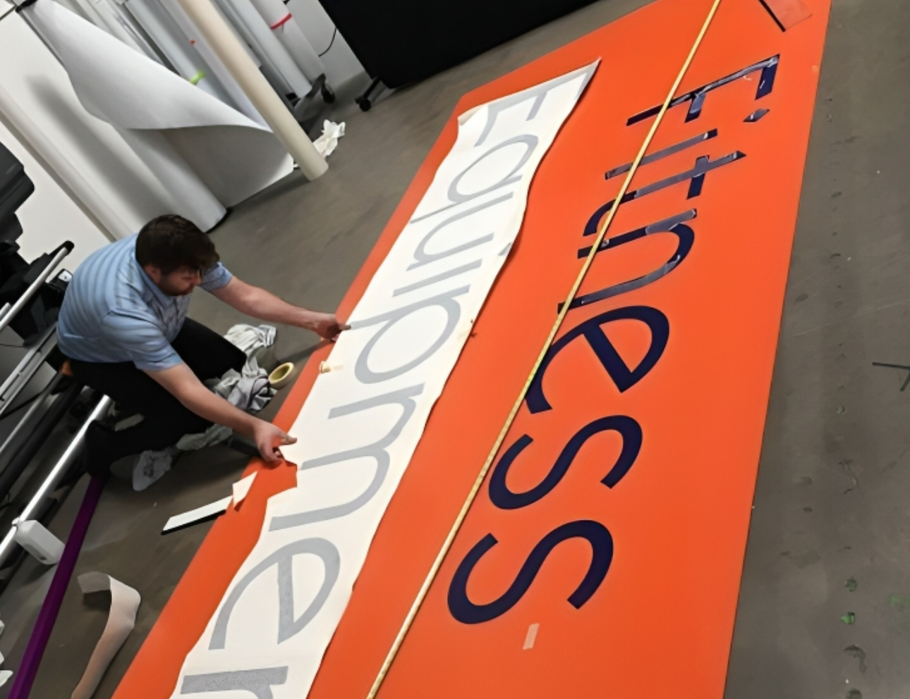 Man assembling large "Fitness Equipment" sign.
