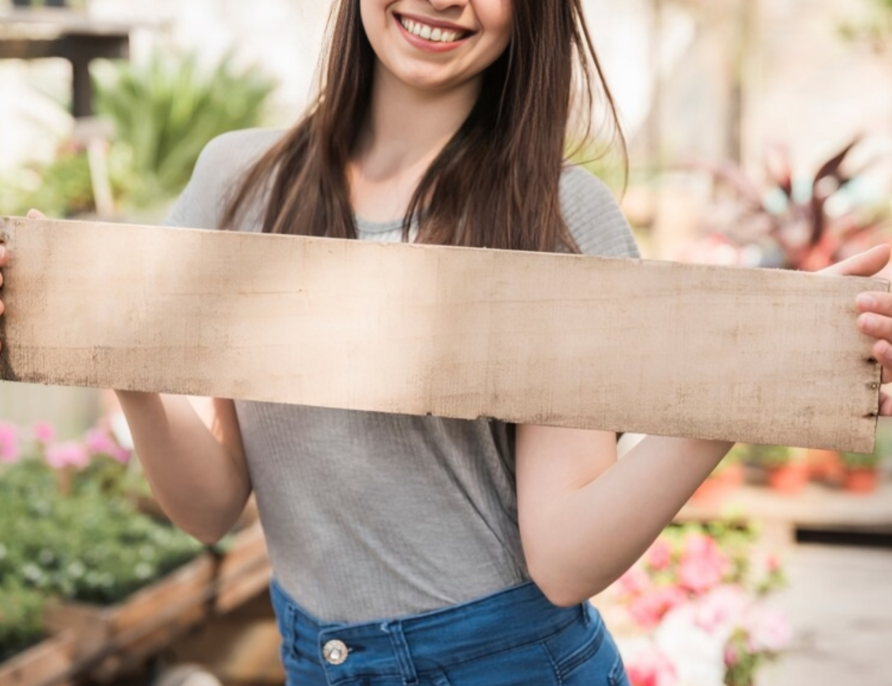 Woman holding blank wooden sign in garden.