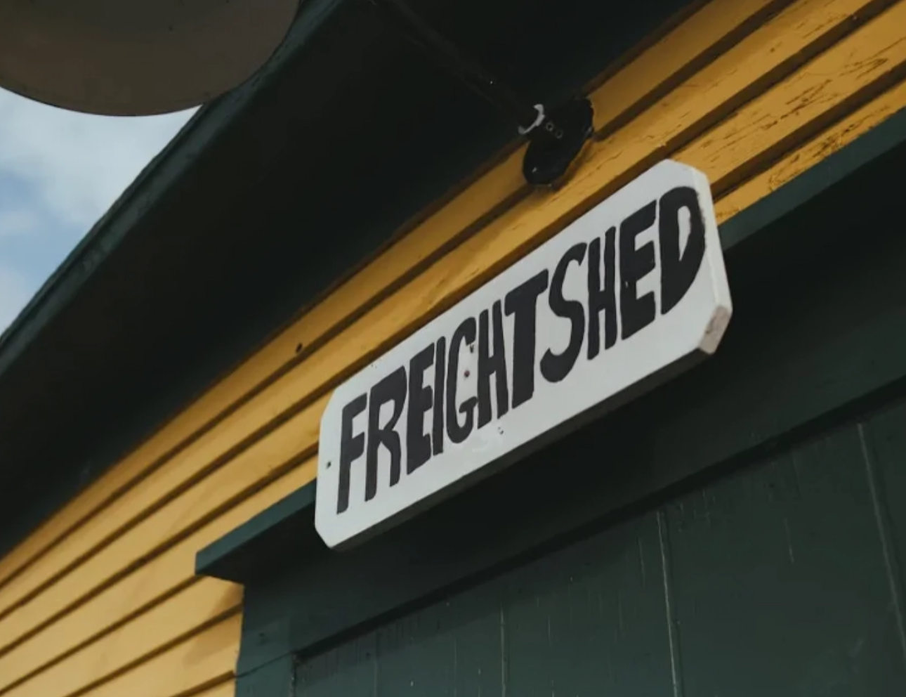 Sign reading "Freight Shed" on yellow building.