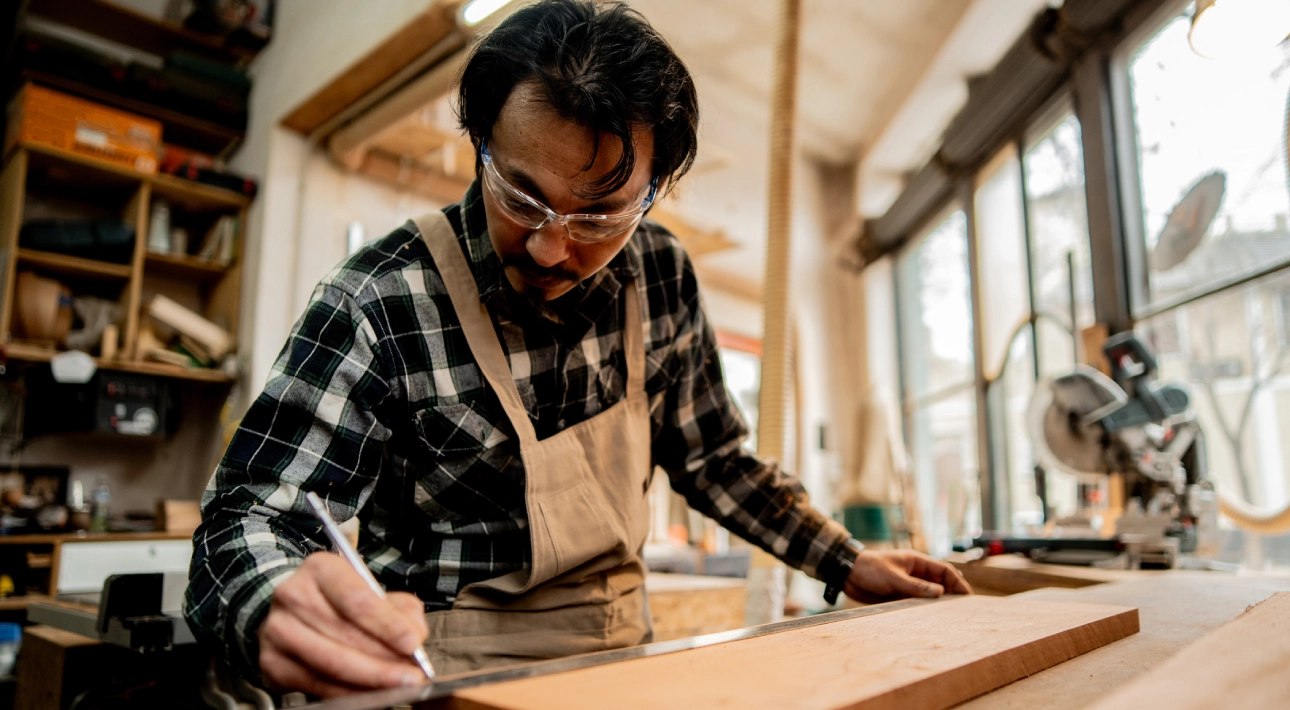 Man measuring wood in a workshop.