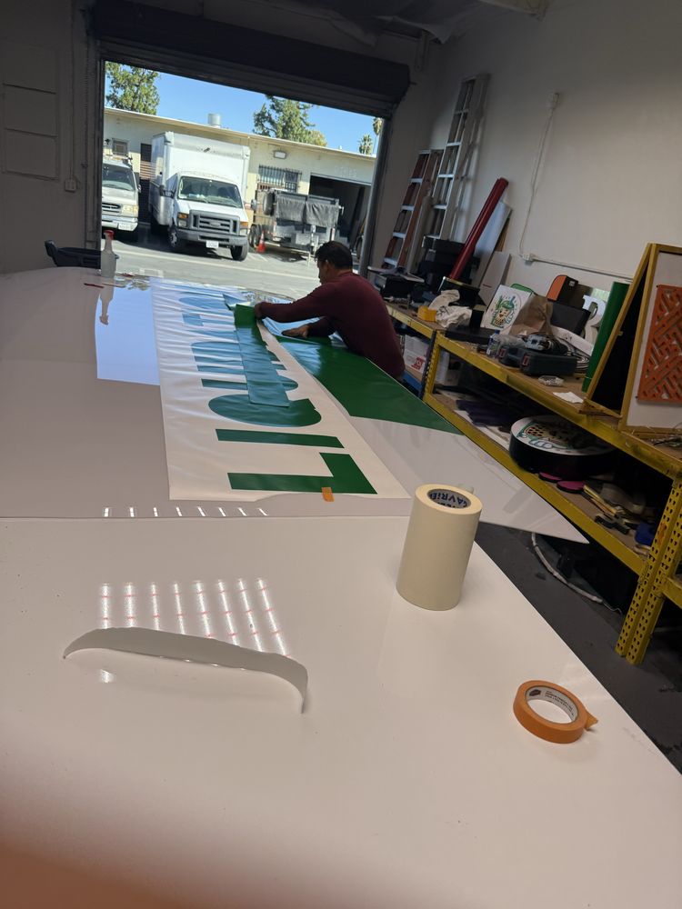Person working on large sign in workshop.
