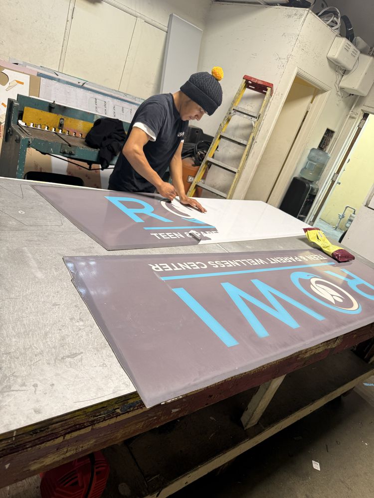 Person working on large sign in workshop.