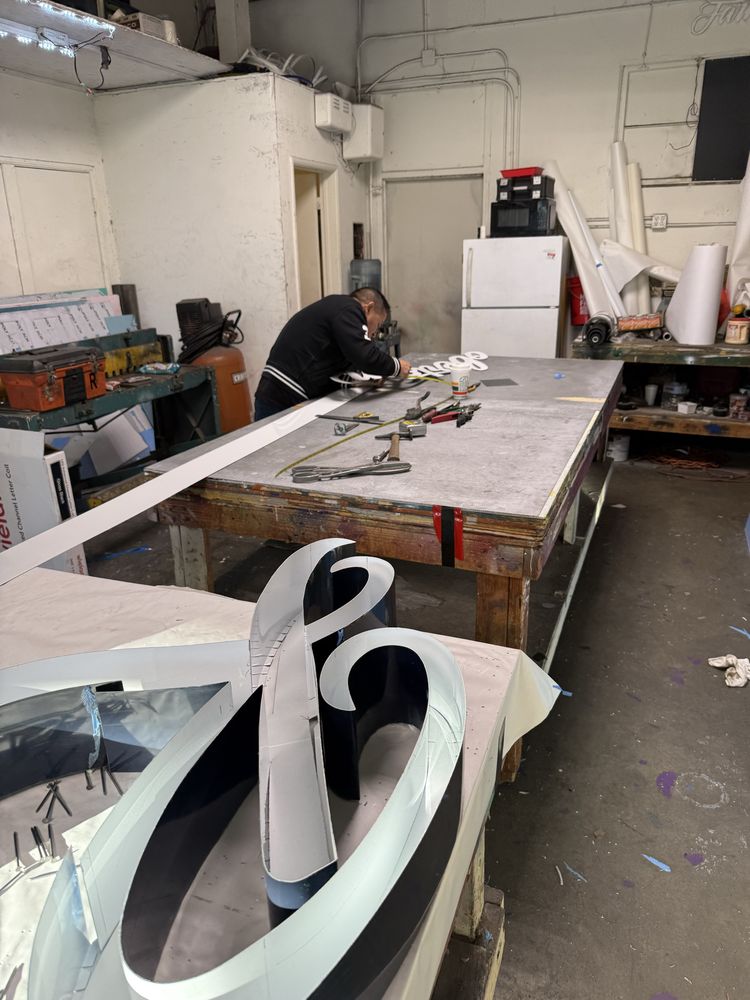 Person working on a large sign in workshop.