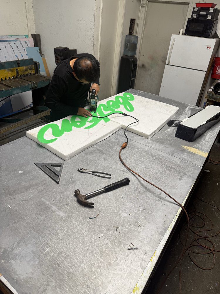 Person working on green sign in workshop.