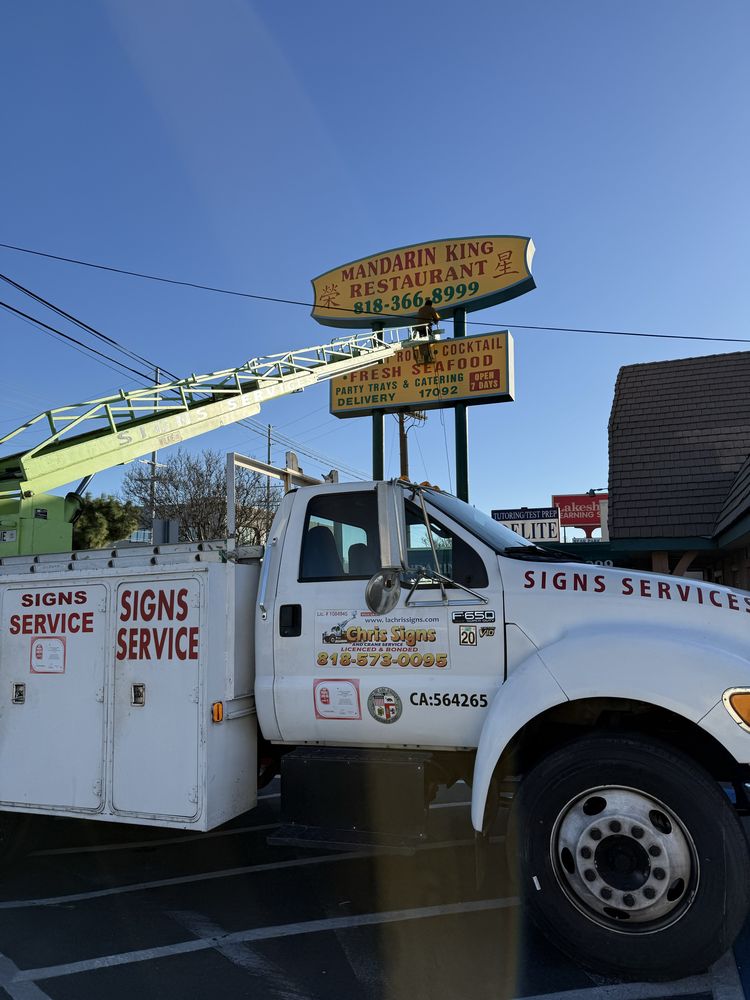 Truck servicing restaurant sign in parking lot.