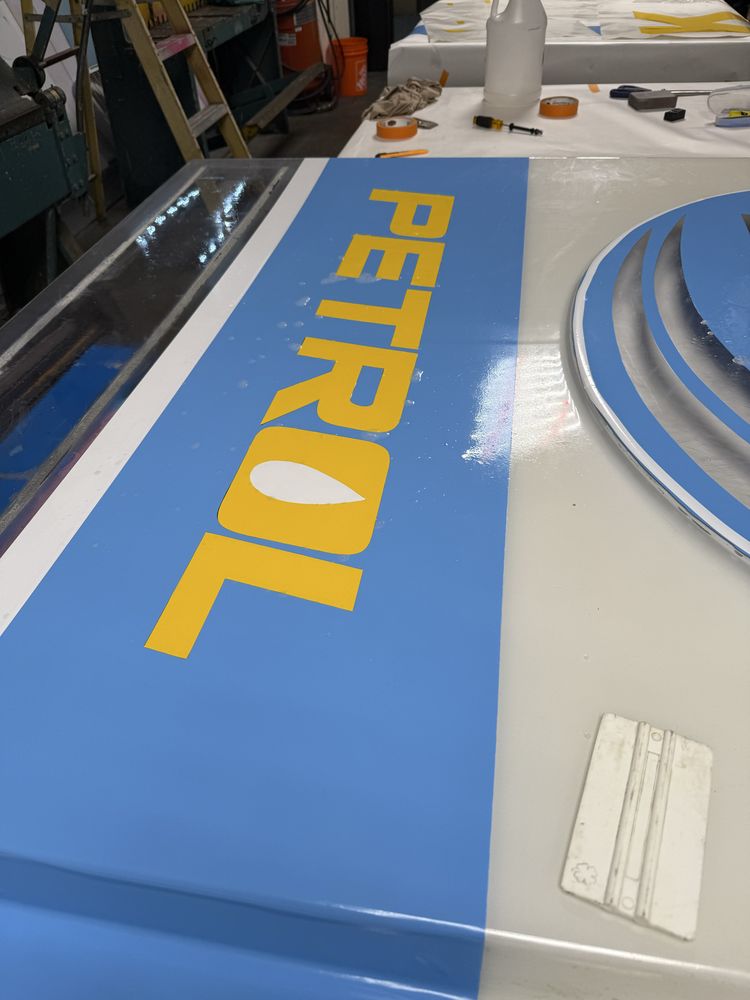 Blue and yellow petrol sign in workshop.