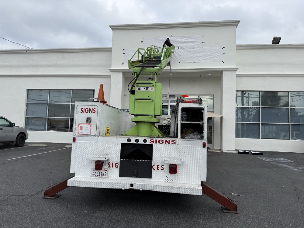 Sign installation truck outside a building.