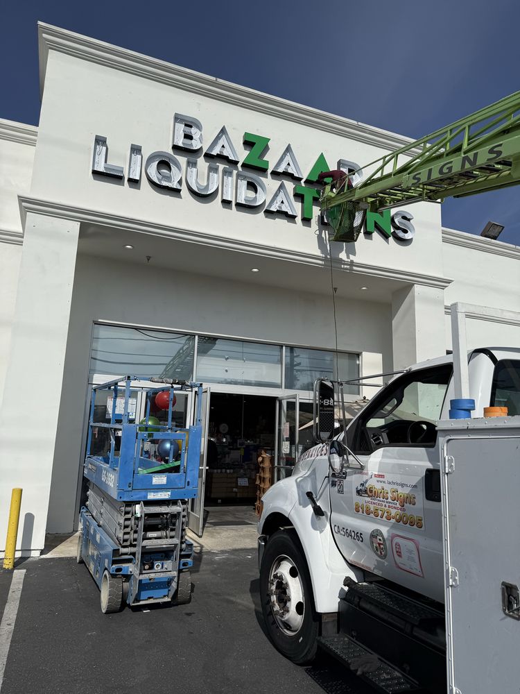 Storefront sign installation with truck and lift.