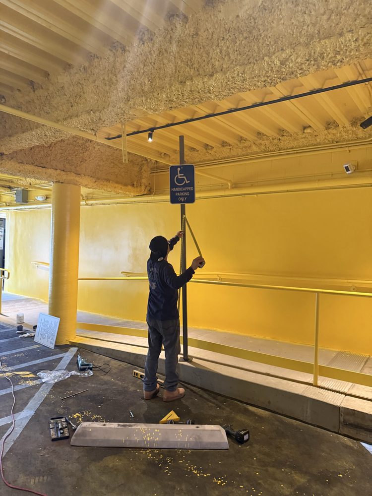 Man installing accessible parking sign indoors.