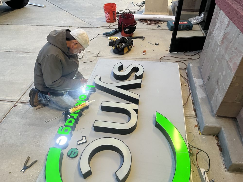 Person working on illuminated sign installation.