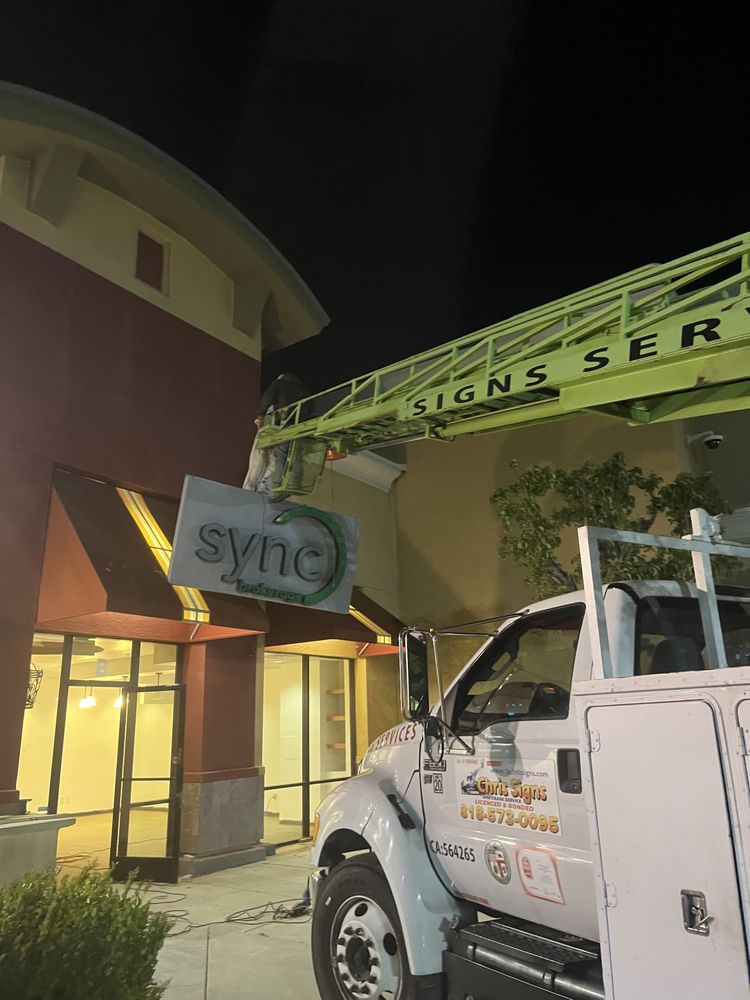 Sign installation at night with crane truck.