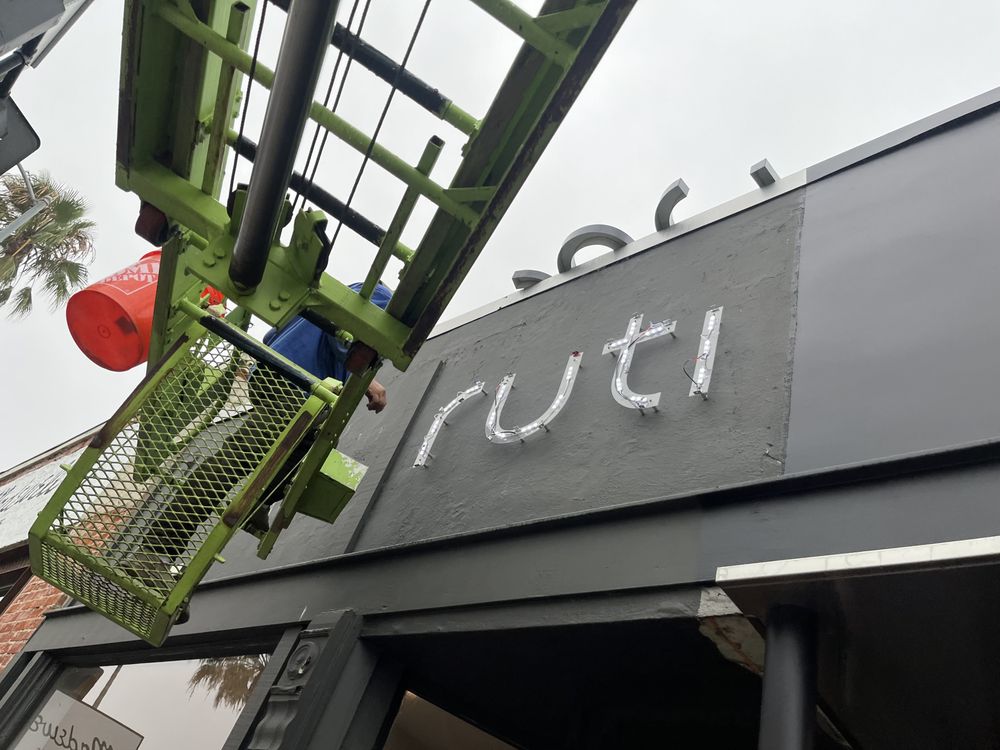 Sign installation on building with crane lift.