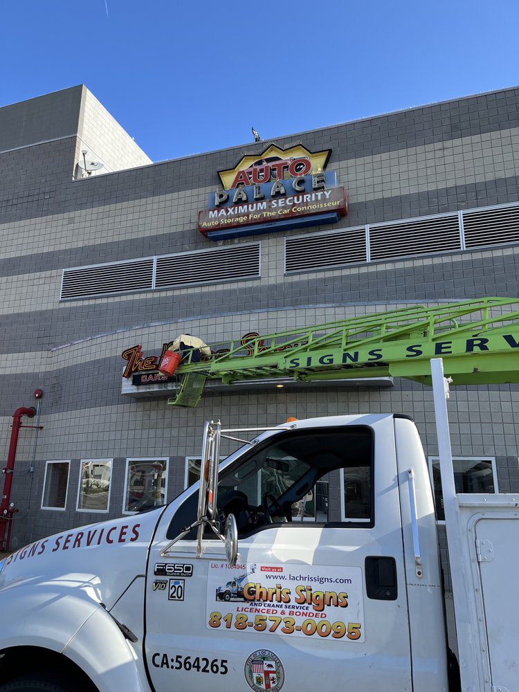 Truck with sign installation equipment outside building.