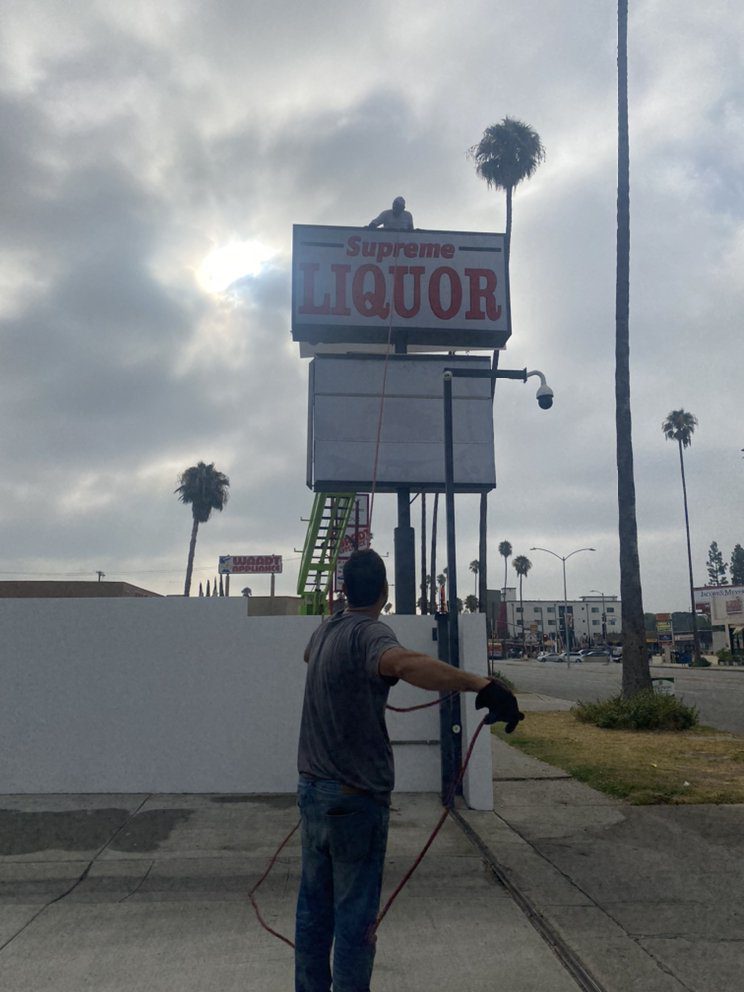 Man working on liquor store sign installation.