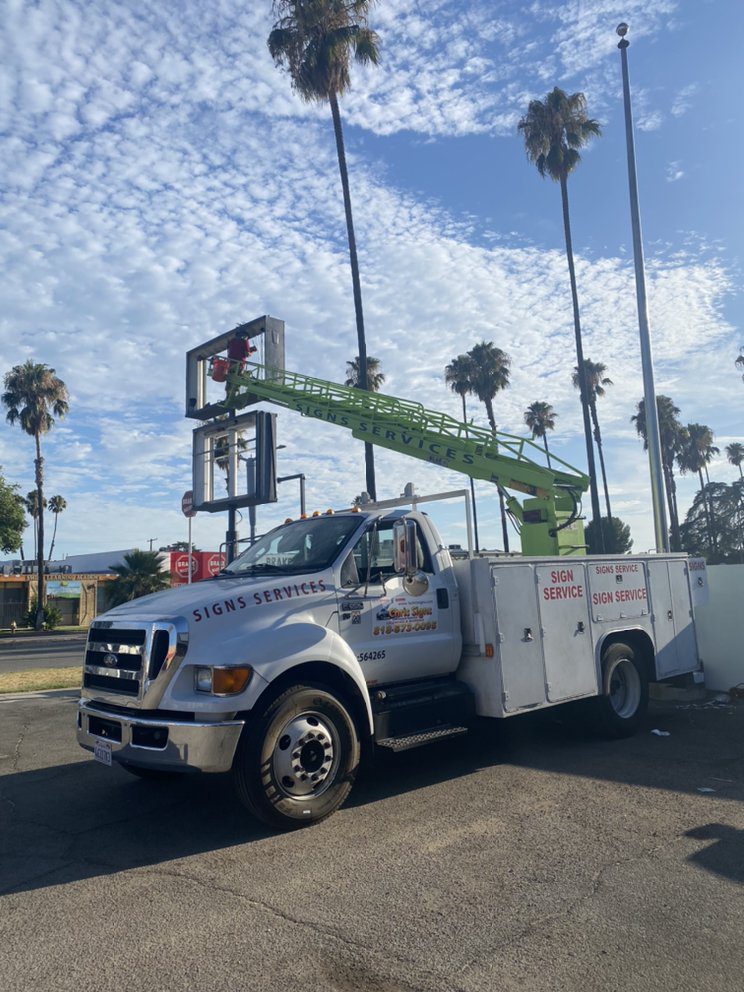 Truck with crane working on sign installation.