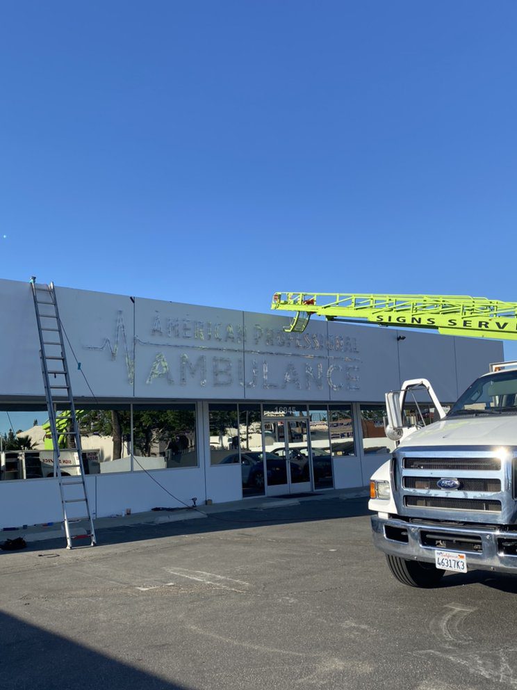 Sign installation at building with truck nearby.