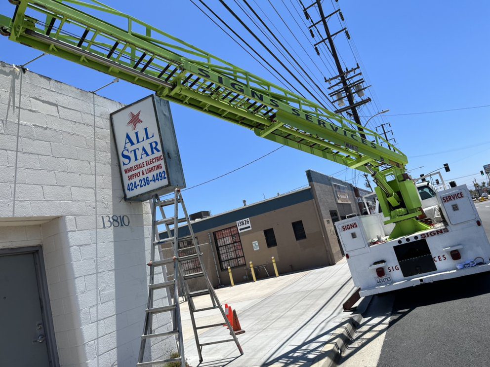 Sign installation with crane and ladder.