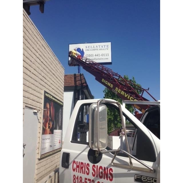 Sign installation truck beside a building.