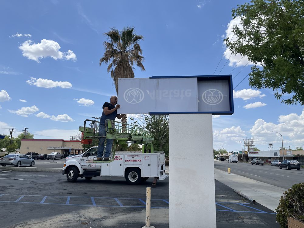 Man working on sign in parking lot.