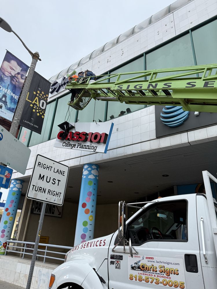 Sign installation on building with crane truck.