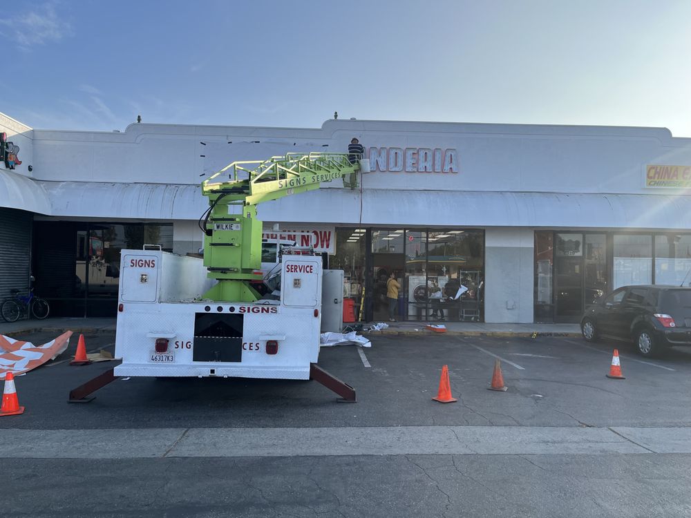 Sign installation on building with crane truck.