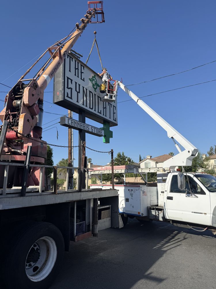 Crane lifting "The Syndicate" sign installation.