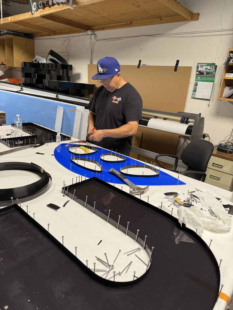 Man assembling large sign in workshop.