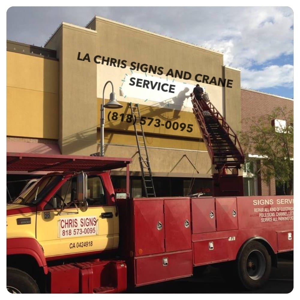 Sign installation using crane on building.