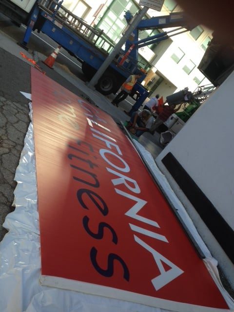 Large red "California Fitness" sign installation.