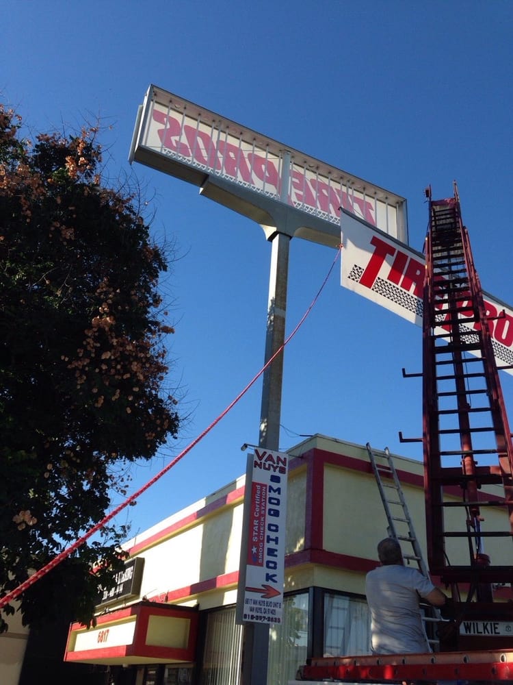Man working on tire shop sign installation.