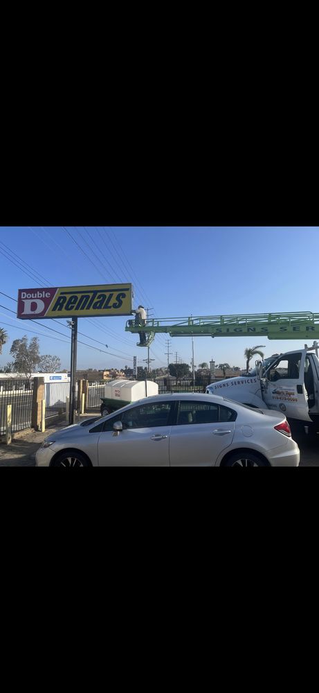 Sign installation with crane and white car.